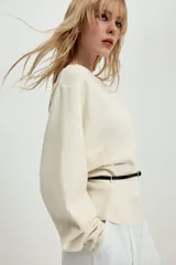 Jersey de punto negro con cuello barco y mangas largas amplias. Presenta un diseño ajustado en la cintura con un cinturón fino integrado que incluye una hebilla metálica dorada.