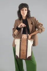 Bolso tote de cuero color marfil con paneles de cuero con textura de cocodrilo color caramelo. Tiene doble asa de mano y correa larga desmontable para usar al hombro o cruzado.
