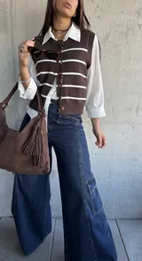 Chaleco de punto en color chocolate con rayas horizontales blancas, diseño sin mangas, cuello redondo y cierre frontal con botones a tono.