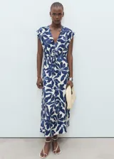 Vestido largo de viscosa y poliamida, con diseño evasé y estampado floral en azul y blanco. Cuenta con cuello de pico, mangas cortas y panel fruncido ajustable con cordón en la cintura.