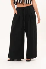 Pantalón negro de pierna súper amplia, confeccionado en denim fino y liviano con caída fluida. Tiene cintura elastizada con lazo regulable, bolsillos laterales y pinzas en la delantera.