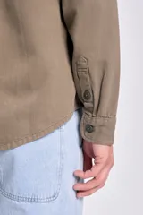 Sobrecamisa de gabardina verde militar, de corte recto, con mangas largas, bolsillos frontales con solapa y botones, y cierre frontal abotonado.