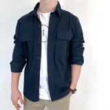 Sobrecamisa azul marino de gabardina, de manga larga con puños abotonados, cuello camisero y cierre frontal con botones. Tiene dos bolsillos de parche en el pecho.