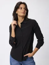 Camisa de manga larga en color negro, con cuello clásico y cierre frontal de botones. Presenta un corte entallado y puños con botones.