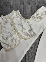 Conjunto de chaleco y pantalón color crudo con bordados de lentejuelas plateadas. El chaleco es sin mangas y el pantalón es de corte recto.