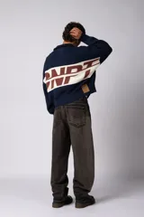 Campera tejida de punto con cierre frontal completo, cuello tipo polo y diseño con franja horizontal en contraste con estampado gráfico. Presenta puños y ruedo acanalados, con corte holgado.