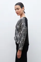 Blusa beige con estampado de arabescos en azul, con escote en V y mangas largas.