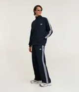 Pantalón deportivo azul marino con cintura elástica, bolsillos laterales y rayas blancas a los costados. Presenta un corte recto y un pequeño logo estampado en la parte superior.