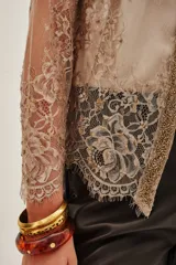 Saco de encaje con diseño floral y detalles bordados en hilo dorado. Presenta mangas tres cuartos, escote en V y bordes con terminación de puntilla. El diseño es abierto al frente con una estructura delicada y elegante.