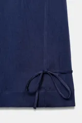 Pantalón ancho de tiro alto color azul marino, con cintura elástica fruncida y bolsillos delanteros. El bajo de las piernas tiene un detalle de lazada o puño vuelto.