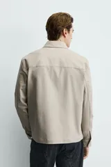 Sobrecamisa negra de corte relajado, confeccionada en tejido con mezcla de algodón elástico. Presenta cuello solapa, cierre frontal de cremallera, bolsillos de plastrón en el pecho y bolsillos de vivo en la cadera.