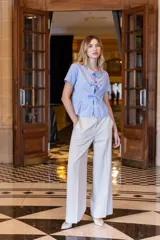 Pantalón de vestir blanco, de pierna recta y ancha, con bolsillos laterales en la parte delantera y pinzas de ajuste en la espalda.