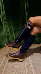 Botas altas de cuero marrón combinadas con gamuza blanca con estampado de vaca, forradas en cuero y con cierre de bronce.