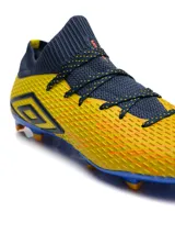 Championes de fútbol Umbro modelo Ignis HG, con diseño de botín de corte medio en color amarillo con detalles en azul marino y suela azul con tapones naranjas.