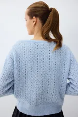 Buzo celeste de punto pointelle con lana, escote bote y hombros descubiertos, mangas largas y diseño holgado.