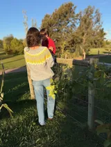 Sweater tejido a mano en mohair, de cuello redondo y manga larga. Presenta un diseño de canesú con patrón geométrico en tonos amarillo y blanco sobre una base de color marrón.
