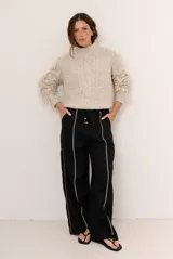 Pantalon de lino color marrón con costuras blancas decorativas a lo largo de las piernas y corte amplio.