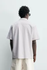 Camisa azul marino de corte regular fit confeccionada en tejido fluido de algodón y lino, con cuello solapa, manga corta, bolsillo aplicado en el pecho y cierre frontal con botones.