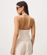 Blusa sastrera color marfil de corte halter con escote en V, cierre frontal con ganchos y bolsillos ribeteados simulados.