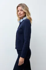 Chaqueta tejida de punto en color azul marino, con diseño de doble botonadura frontal y bolsillos aplicados. Presenta un cuello desmontable en tono claro y mangas largas.