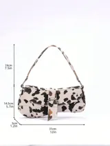 Cartera baguette con estampado de vaca en blanco y negro, con correa de hombro y cierre con hebilla metálica.