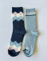 Pack de dos pares de medias de algodón, una azul marino con rombos en tonos rosa, celeste y blanco, y otra celeste con lunares blancos y rayas en el borde superior.
