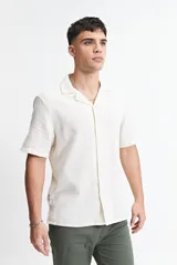 Camisa de manga corta color crema con textura, cuello clásico y calce regular.