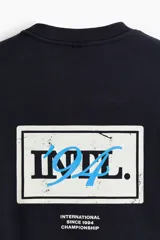 Buzo negro de algodón con diseño estampado en el pecho que incluye texto pequeño y el número '94 en celeste, corte holgado y hombros caídos.