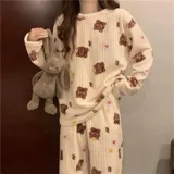 Conjunto de pijama de dos piezas confeccionado en plush suave, compuesto por una remera de manga larga y pantalón largo. Presenta un diseño estampado de duraznos sobre fondo color crema.
