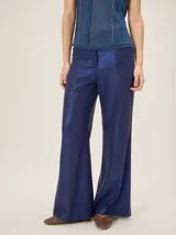 Pantalón de lino color azul metalizado, de corte sastrero, tiro medio y pierna recta amplia.
