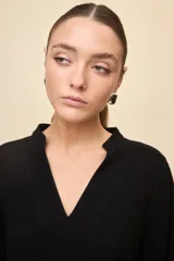 Vestido corto negro de silueta relajada, con escote en V y mangas 3/4 levemente abullonadas.