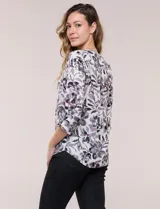 Blusa de gasa estampada de la marca Zac & Rachel, con diseño floral en tonos azul, celeste y verde sobre base blanca. Presenta escote en V con abertura y botones frontales, y mangas largas de largo regulable con presilla.