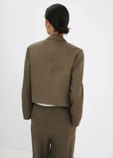 Chaqueta corta de lino color verde militar, de corte recto, con cuello alto camisero y cierre de doble botonadura.