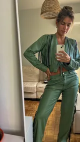 Pantalón de cuero sintético color verde safari, corte recto, con flecos largos en los laterales.