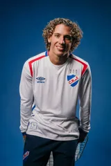Camiseta de fútbol Umbro del Club Nacional de Football, modelo Home de manga larga. Diseño blanco con detalles en rojo y azul en los hombros y puños. Incluye logo de Umbro, escudo del club y detalles conmemorativos en el pecho.