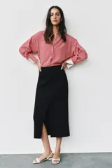 Camisa de cuello solapa y manga larga con rayas verticales rojas y blancas, con puños anchos blancos contrastantes y cierre frontal de botones.
