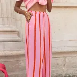 Pantalón holgado de tiro alto, color rosado con rayas verticales rojas, de pernera ancha y cintura elastizada.