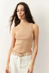 Top sin mangas de tejido de punto acanalado color beige, con cuello alto y pequeñas aberturas en la zona del escote.