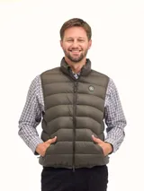 Chaleco puffer de cuello alto, color verde militar, con cierre frontal y bolsillos laterales. Presenta un diseño acolchado horizontal y logo circular en el pecho.
