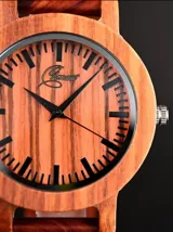 Reloj de pulsera con caja, esfera y malla de madera de sándalo rojo, con marcadores y manecillas negras. Presenta un diseño circular con corona lateral.