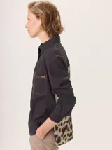 Camisa de manga larga con diseño combinado. Presenta mangas y parte superior delantera y trasera en color negro liso, mientras que el panel central de la espalda destaca por un estampado animal print de leopardo. Cuenta con cuello clásico, cierre frontal de botones y puños abotonados.