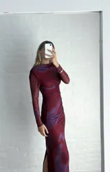 Vestido midi de microtul con diseño drapeado lateral, cuello alto y mangas largas. Presenta un estampado tipo tie-dye en tonos bordó y violeta.
