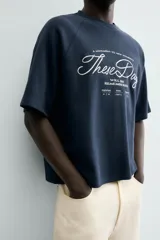 Camiseta de manga corta, cuello redondo y calce relajado, confeccionada en tejido con estructura waffle de color azul marino. Presenta estampados y bordados combinados a contraste en el delantero con texto en blanco.