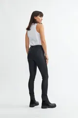 Pantalón chupín de tiro medio color negro con acabado engomado.