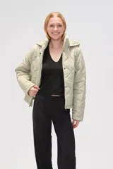 Campera acolchada de color beige con diseño de rombos, cierre frontal con botones a presión, cuello alto y capucha ajustable con cordones.