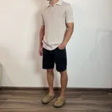 Chomba de tejido de punto con textura, color beige, de manga corta y cuello polo con cierre frontal parcial.