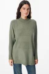 Sweater de punto color verde oliva, con cuello alto, corte holgado y mangas largas con puños acanalados extendidos hasta el codo.