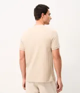 Remera de algodón peruano color beige con textura de rayas verticales, cuello redondo y mangas cortas.