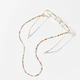 Correa para lentes con cuentas de colores y terminales dorados. Incluye un dije redondo dorado con la marca Meller grabada.