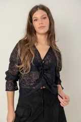 Blusa de encaje negro con escote en V, mangas tres cuartos y detalle de fruncido central con cordón ajustable.